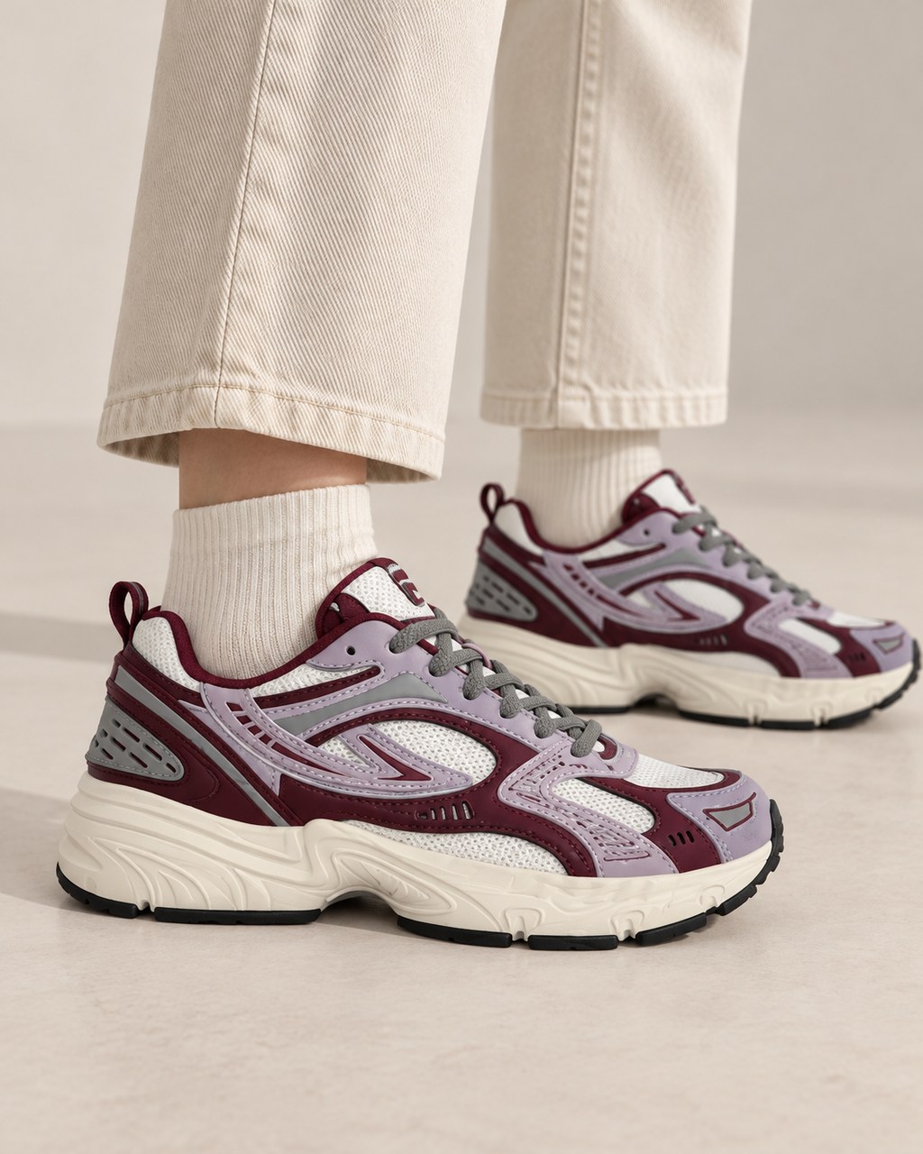 Sneakers FILA grigie e bordeaux indossate, vista laterale