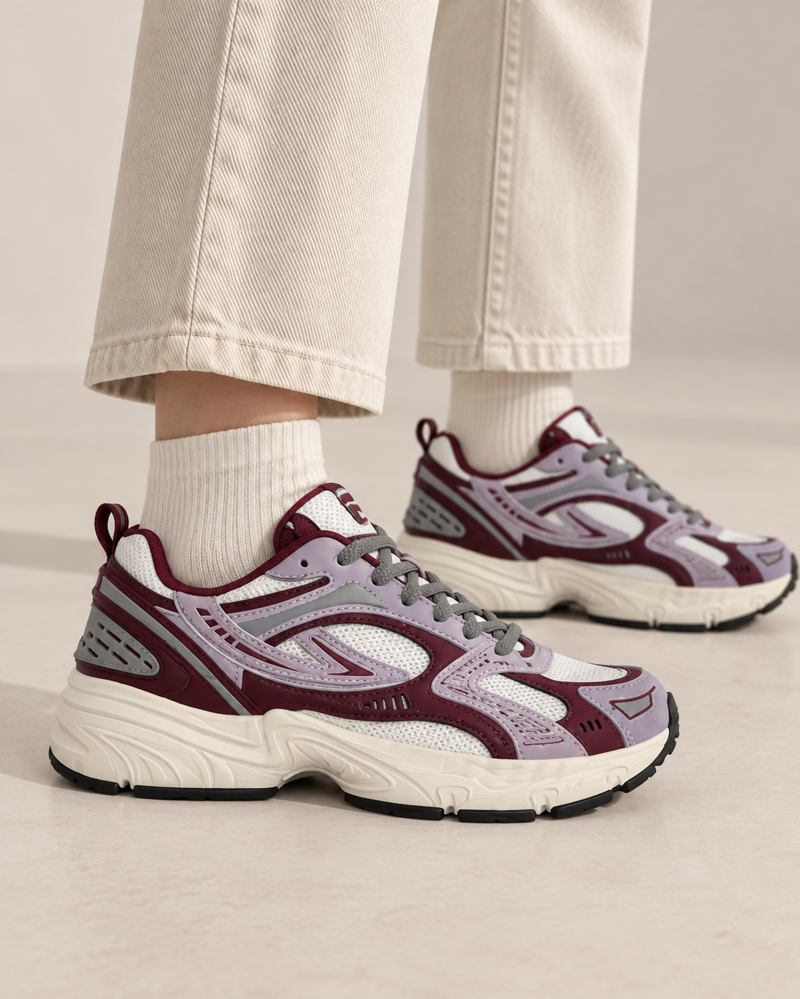 Sneakers FILA grigie e bordeaux indossate, vista laterale