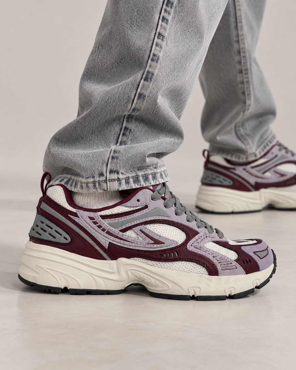 Sneakers FILA grigie e bordeaux indossate, dettaglio in movimento