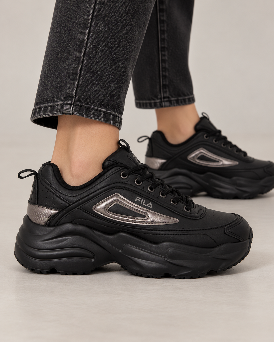 Sneakers FILA nere con dettagli argento indossate