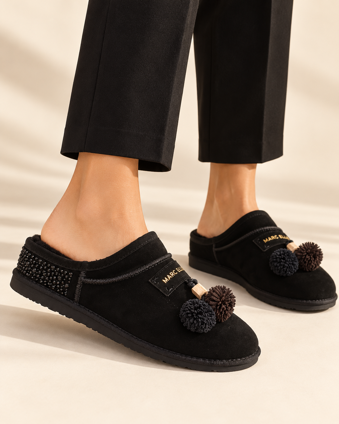 Sabot Marc Ellis nero indossato, con strass laterali e charm a pompon
